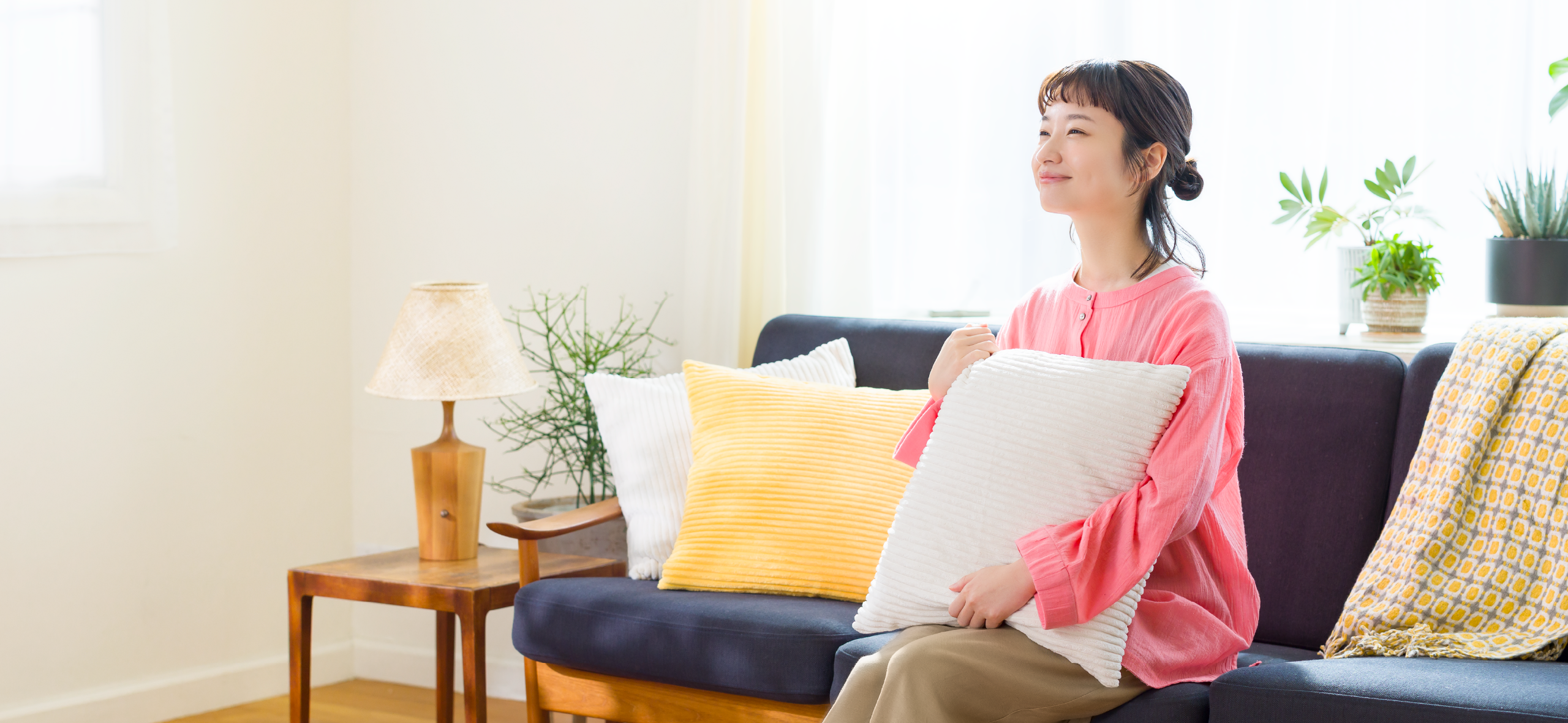 藤間さんがソファに座りクッションを抱えている写真