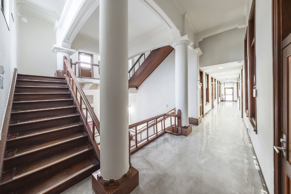 2階ホール。円柱の足元には木製台座。階段や建具、手すりも同じ色合いの木製で統一