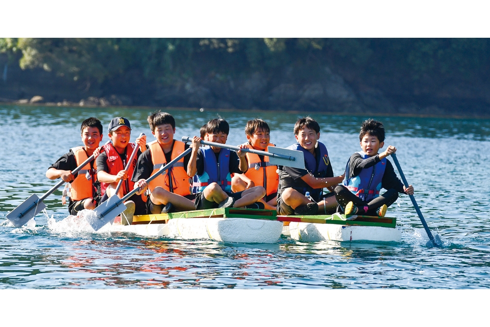 「いかだ集会」は、1チーム8人が力を合わせて、一周2kmの巴理島を手づくりのいかだでぐるりと一周し、速さを競い合う