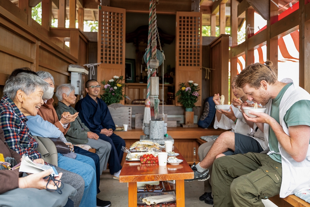箸を上手に使って麺をすするフランス人お遍路さんの様子に、目を細める住民たち。「おいしい」の言葉が何よりのご褒美となる