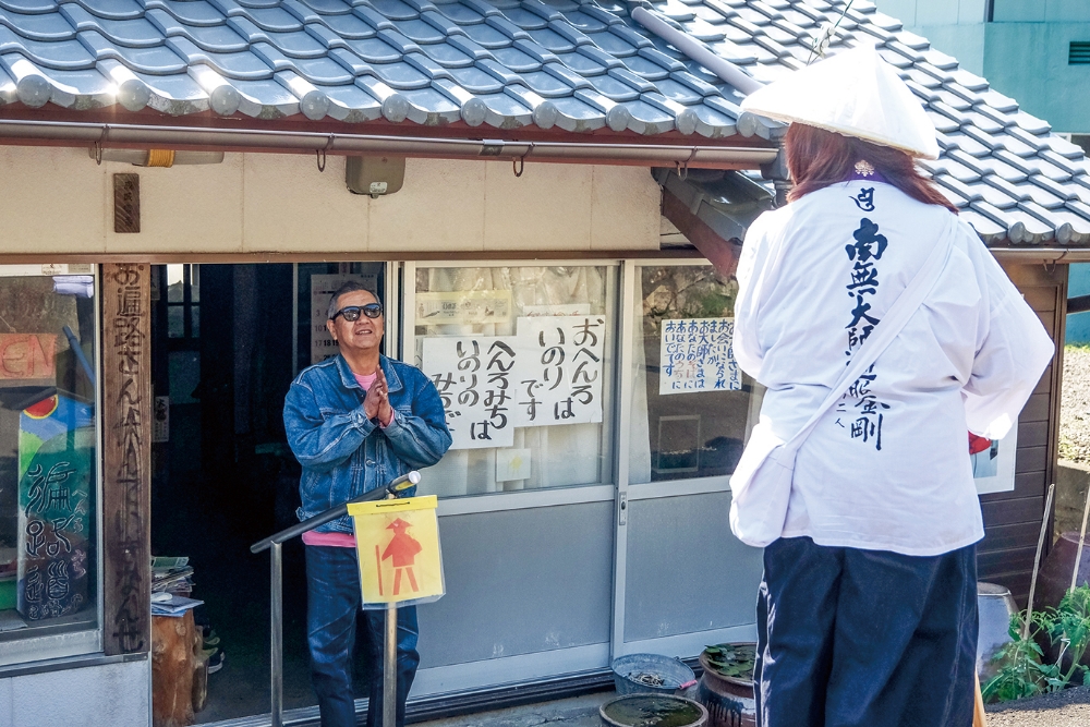 有田さんと話すことで、晴れやかな気持ちになったお遍路さん。合掌しながら、有田さんは笑顔で出立を見送る